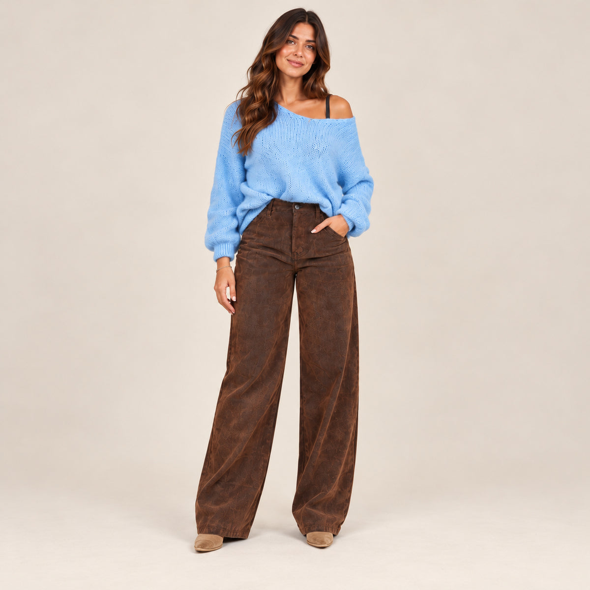 Maglioncino Bardot azzurro oversize con spalla scoperta abbinato a jeans marrone, vista frontale