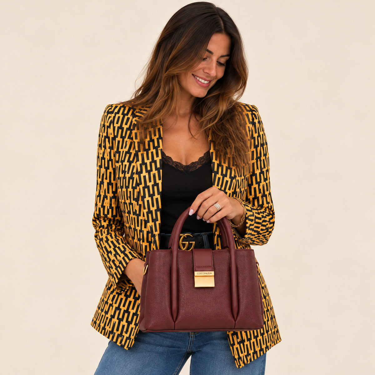 City Bag Coconuda Borgogna tenuta per i manici, abbinata a un blazer fantasia