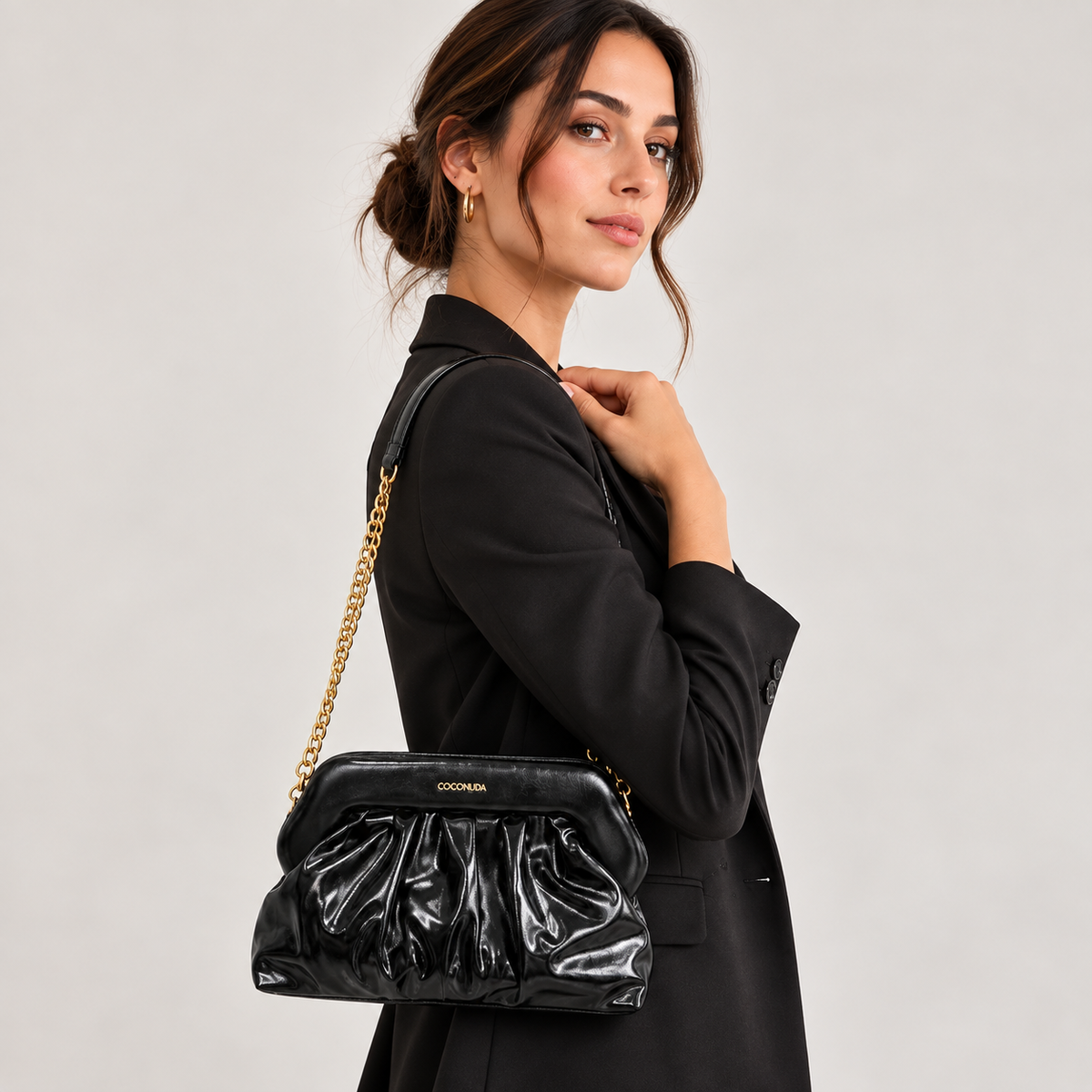 Coconuda Clutch Pouch Nero - indossata a spalla con catena dorata